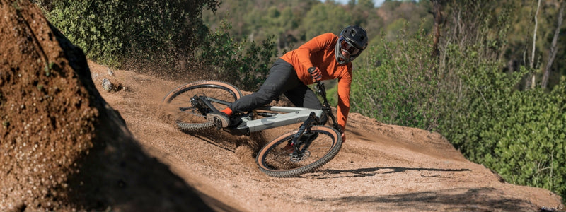 Mies ajaa Hepha-sähkömaastopyörällä maastossa alamäkiajoa