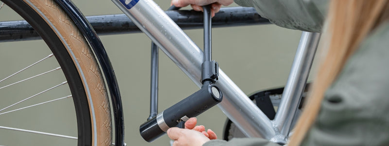 Nainen lukitsee pyörää tankoon u-lukolla