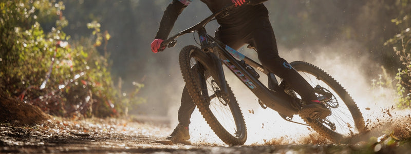 Mies äkki jarruttaa maastopyörällään, yllään pitkälahkeiset  pyöräilyhousut.