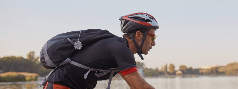 Mies pyöräilee pyöräilyreppu selässä ja kypärä päässä