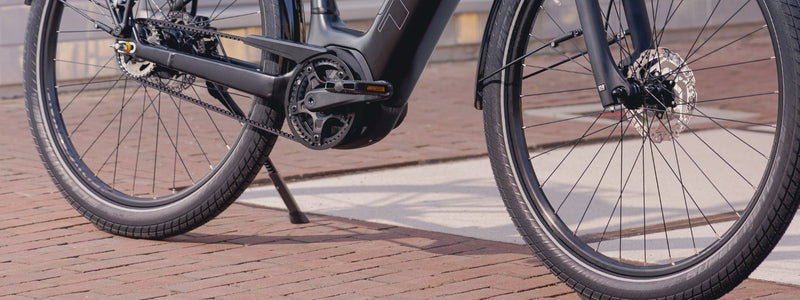 Kuvassa pyörä joka on parkkeerattu nojaamaan seisontatukea vasten