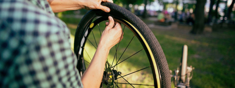 Mies asentaa vanne teippiä pyöränsä renkaaseen